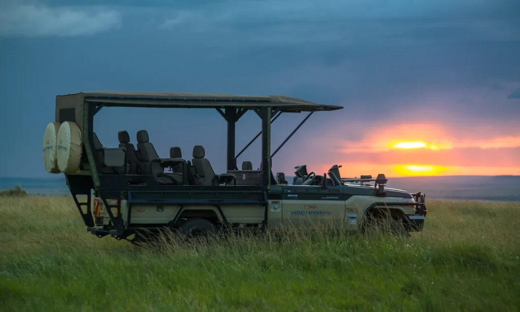 Open-sided safari Land Cruiser parked on grassland at sunset